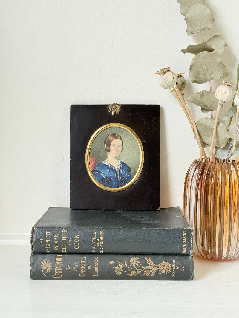 19th century watercolour miniature portrait of woman in blue dress, oval ebonised frame, styled on white background