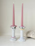 Pair of vintage floral ceramic candlesticks with rose candle cups and pink taper candles styled on a white surface