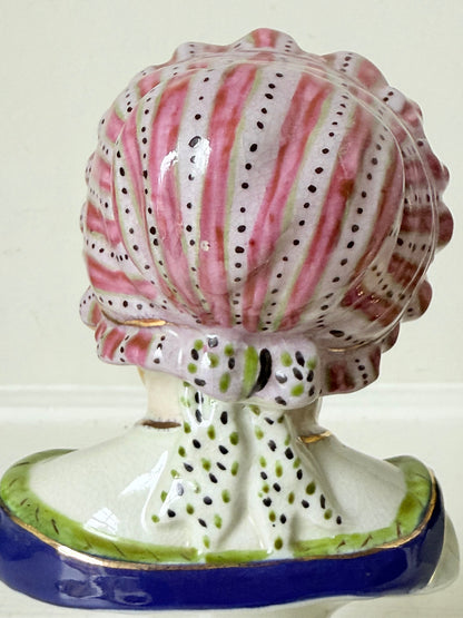 Hand painted Victorian Staffordshire ceramic children busts on white surface, photographed beside dried stems.