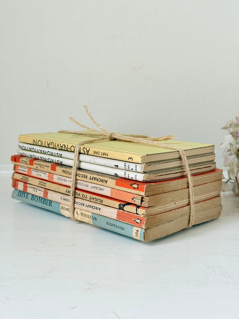 Bundle of vintage Penguin paperback books in orange and cream tones tied with twine, photographed on a white surface