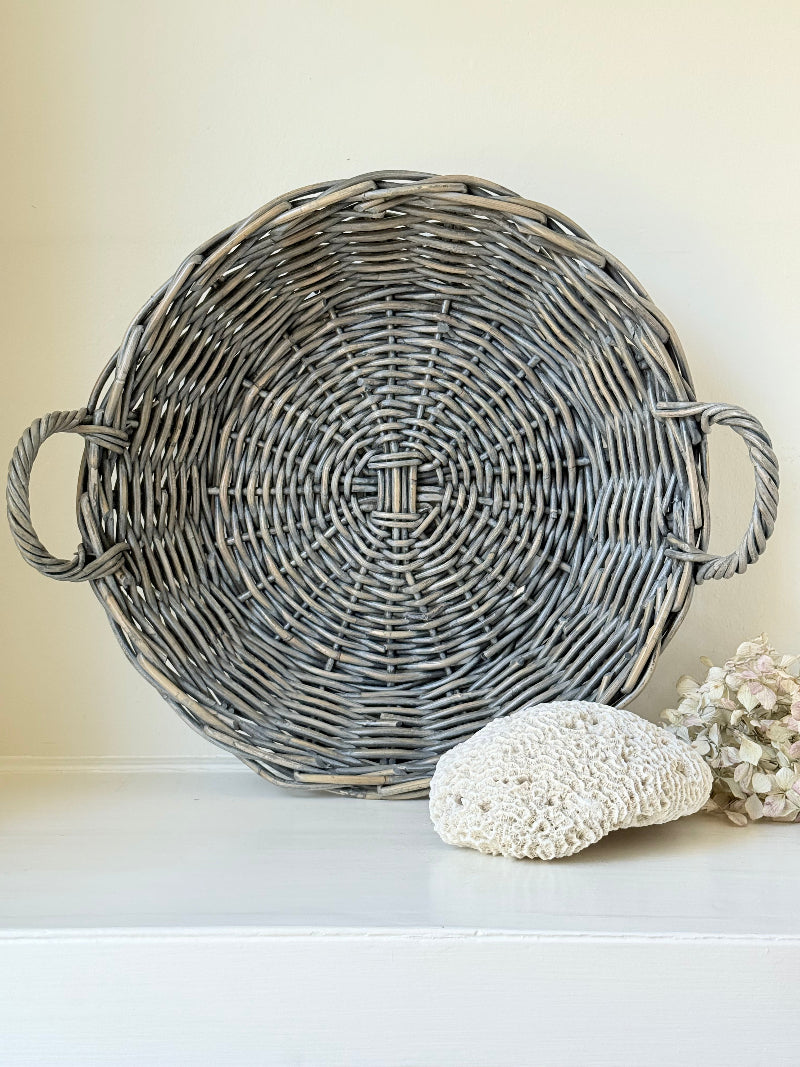 Large vintage woven basket with handles, photographed on a white surface