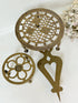 Vintage brass trivet trio with ornate cutwork designs and aged patina, photographed on a white surface