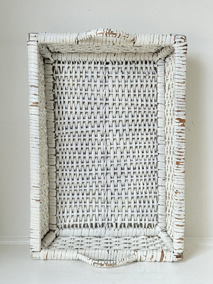 Vintage white painted wicker tray with woven handles photographed on a white surface