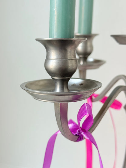Five arm pewter style metal candelabra with aged silver finish styled with blue green taper candles on white surface
