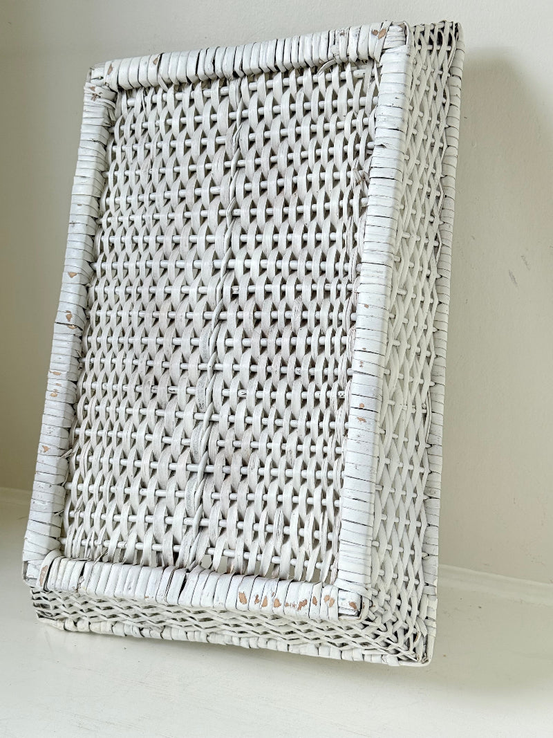 Vintage white painted wicker tray with woven handles photographed on a white surface