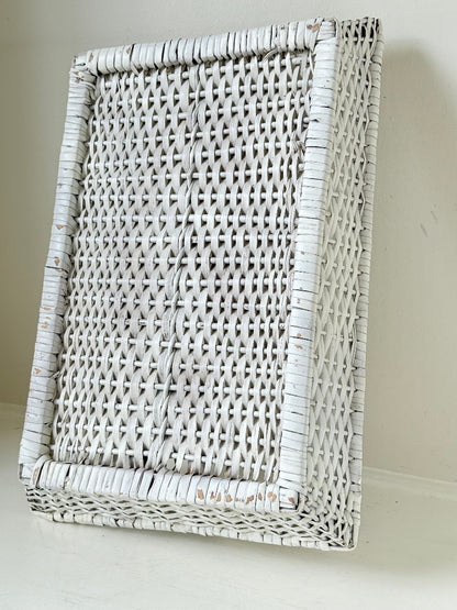 Vintage white painted wicker tray with woven handles photographed on a white surface