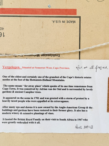 A close-up of a vintage paper document or postcard with printed text, a red stamp, and handwritten notes, laid on a tan paper background.