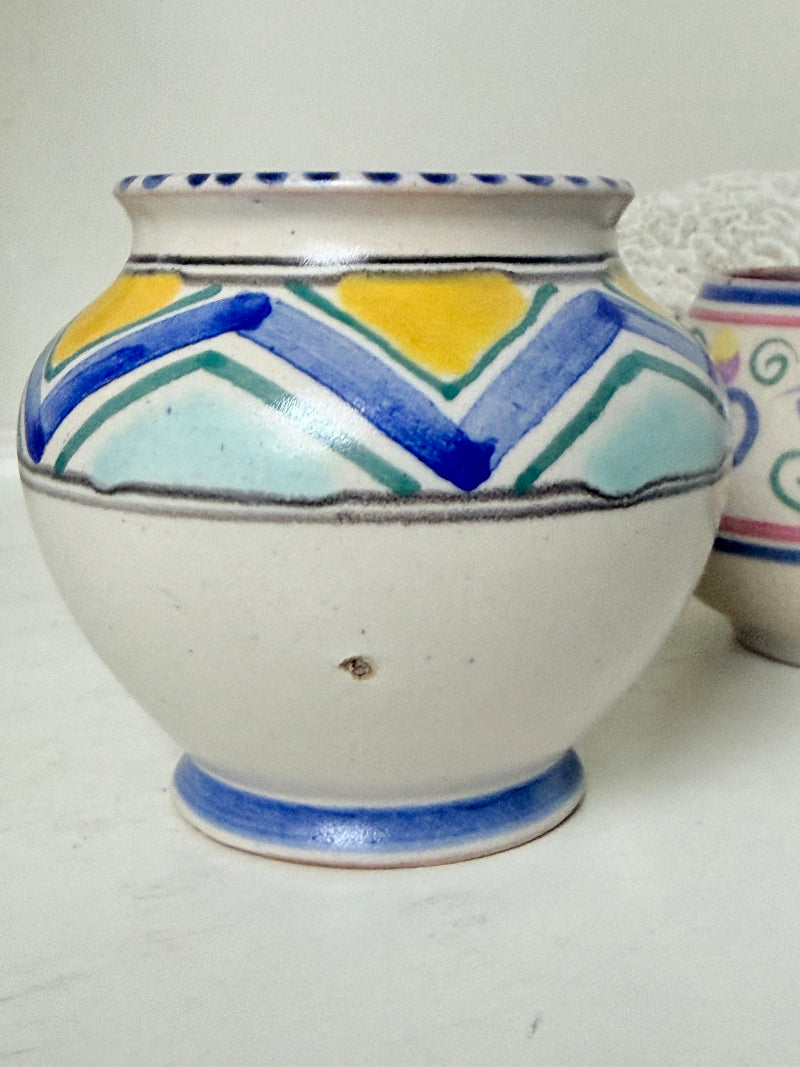 Pair of vintage studio pottery pots in blue green and pink glaze photographed on a white surface