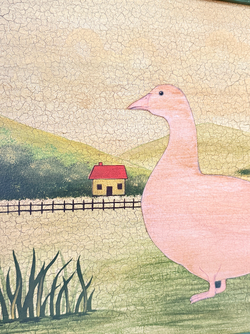 A hand-drawn style illustration of a large pink goose standing in a grassy field, with a small red-roofed house, fence, hills, and cracked beige sky in the background.