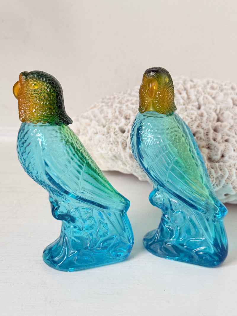 Pair of vintage Avon turquoise glass parrot bottles with green amber stoppers photographed on a white surface