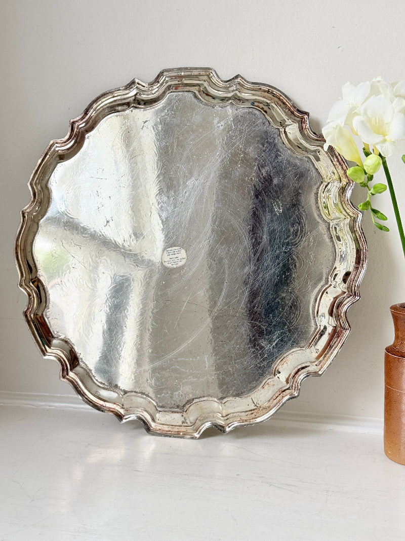 Vintage silver toned round serving tray with piecrust edge, aged patina and decorative scalloped rim for interior styling