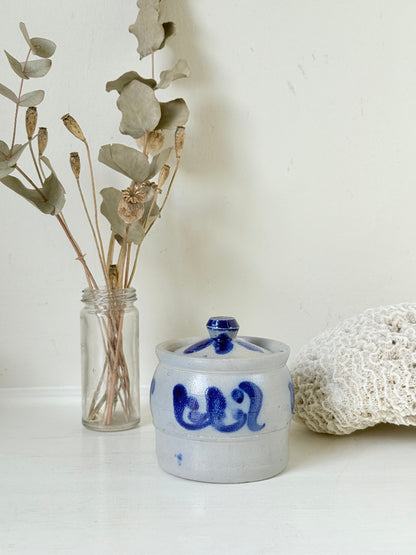 Vintage lidded pottery jar with hand painted blue floral decoration, photographed on a white surface