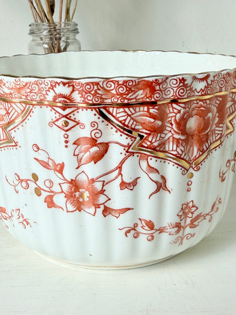 vintage porcelain sugar bowl with coral transfer design and gilt rim on white surface