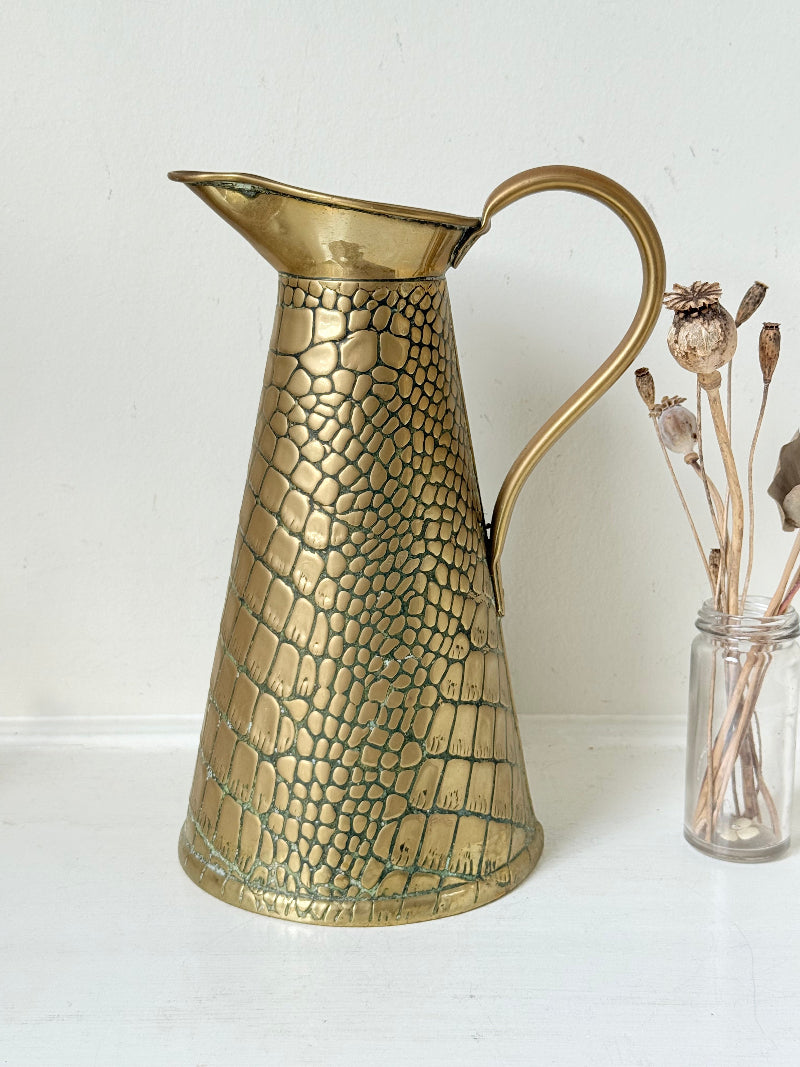 Vintage brass jug with alligator patterned surface, photographed against a white background.