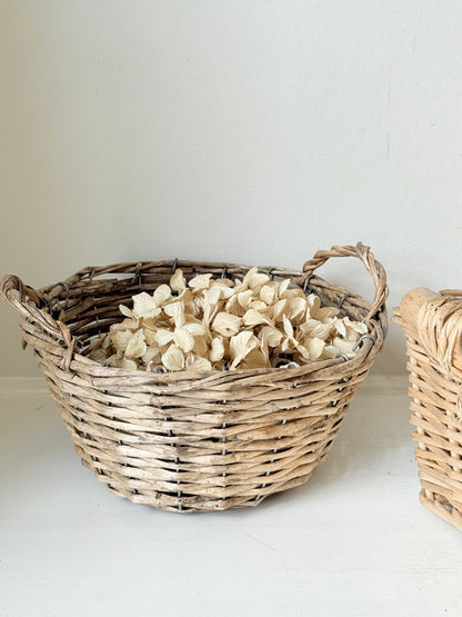 Set of three vintage woven willow baskets in natural tones photographed on a white surface