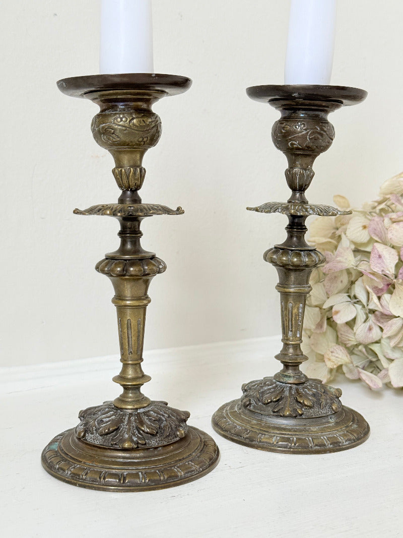 pair of antique brass candlesticks with turned detailing on white surface
