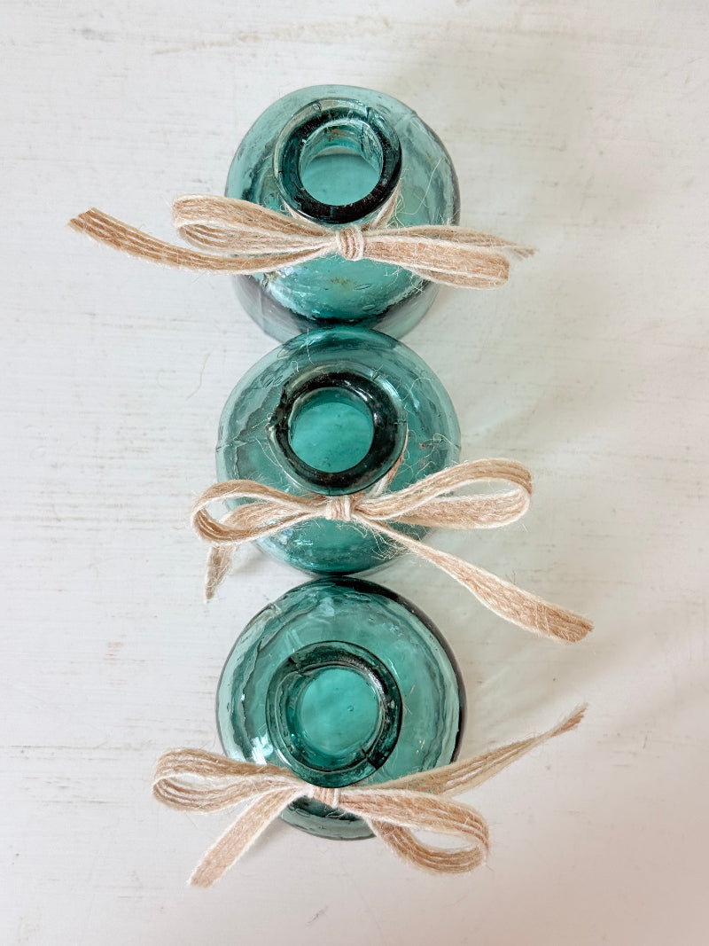 Set of antique green glass ink bottles with rounded forms, photographed on white surface.