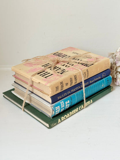 Bundle of vintage books in blue and neutral tones tied with twine, photographed on a white surface