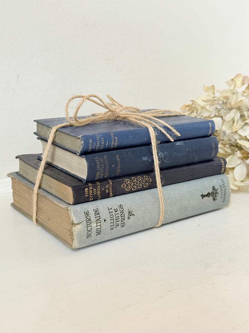 Vintage decorative book bundle in navy, grey, and cream tied with twine, photographed on a white surface