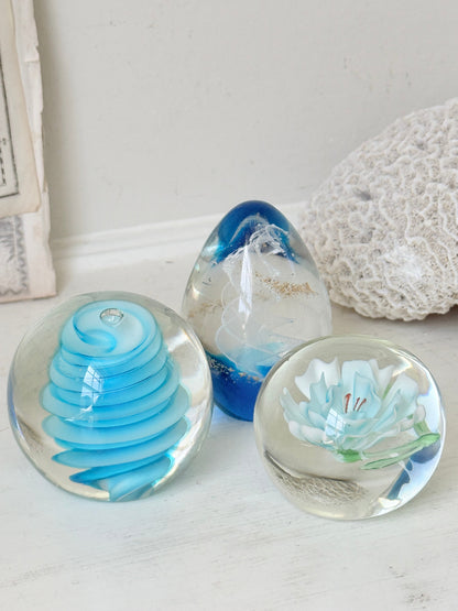 Trio of vintage turquoise blue glass paperweights with swirl, ribbed and floral detail in clear coloured glass