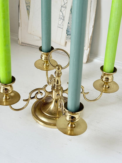 Brass five light candelabra with scrolled arms and a central ring handle on a domed base, photographed on a white surface