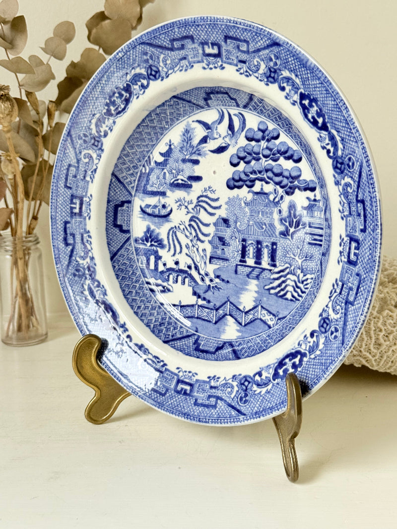 Antique Blue Willow serving bowl with cobalt transfer pattern shown on a white surface.