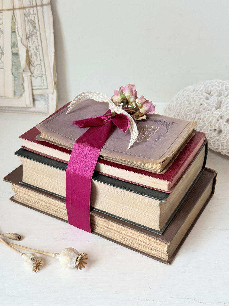 Vintage decorative book bundle with pink ribbon, dried flower detail and aged hardback covers for shelf and table styling