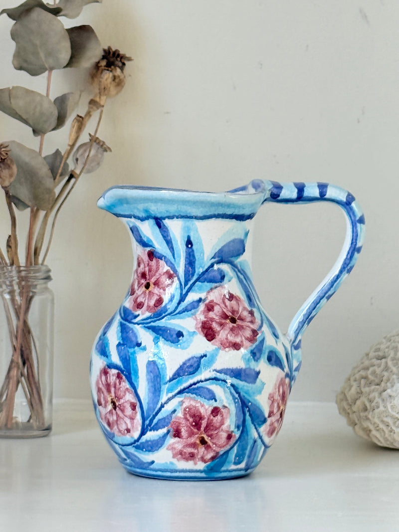 Portuguese studio pottery jug with blue and pink hand painted floral design, photographed on a white surface