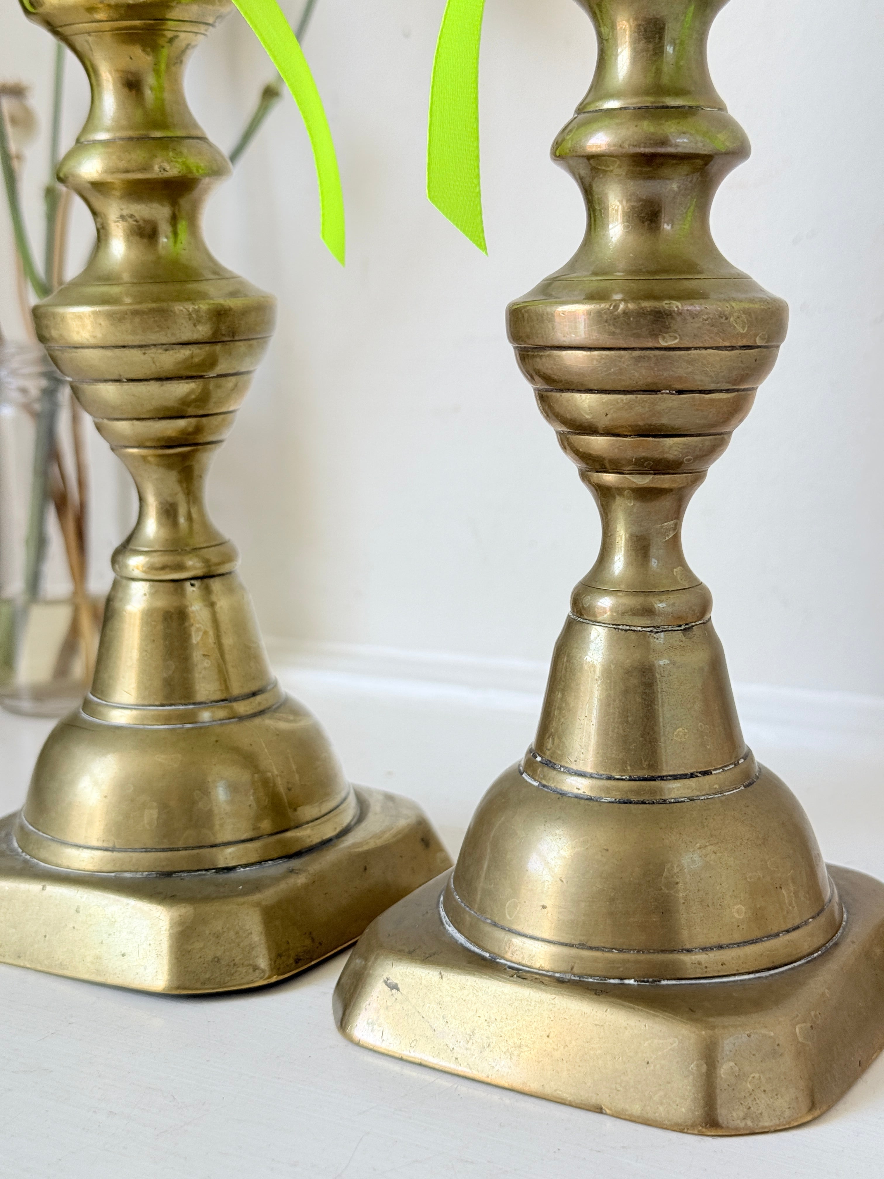 Pair of vintage brass candlesticks with turned stems and square bases, photographed on a white surface