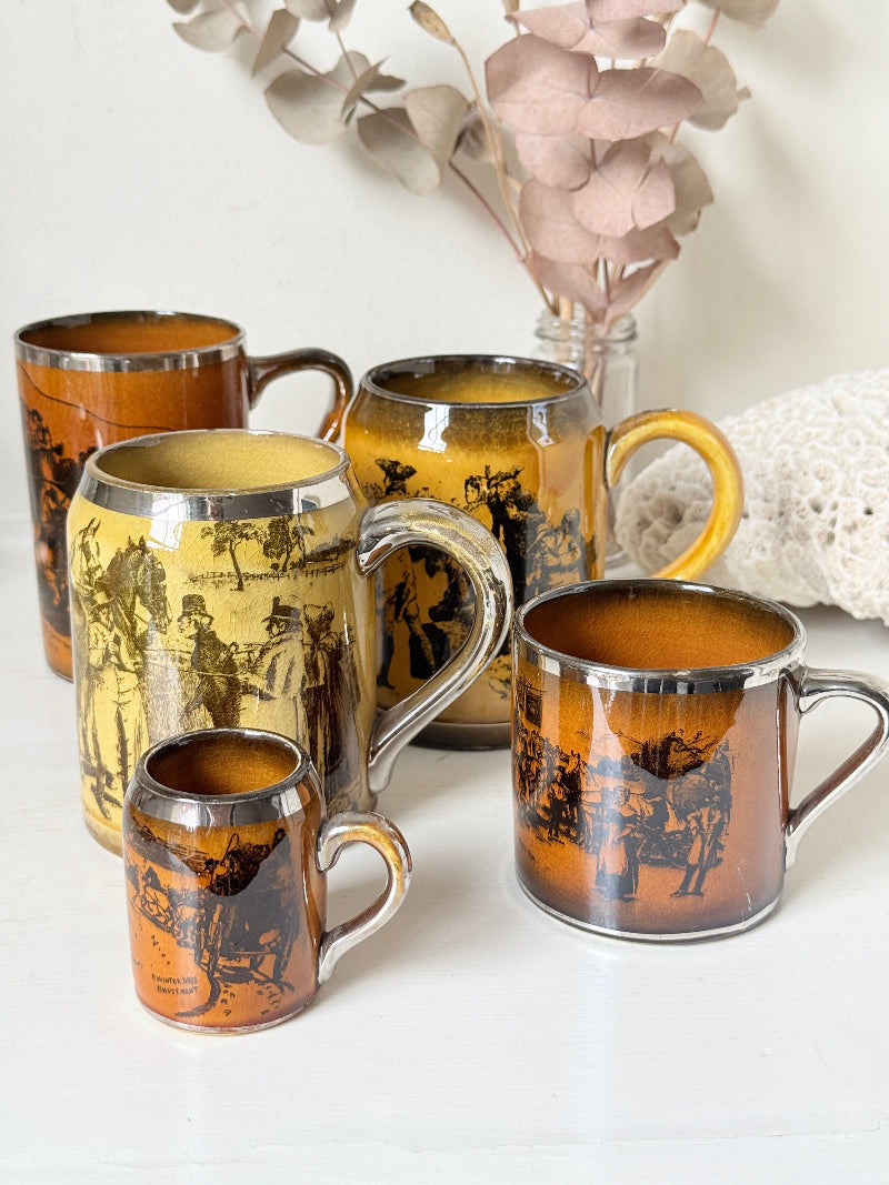 Set of 5 Ridgways stoneware mugs photographed on a white surface in amber brown glaze with black Coaching Days and Coaching Ways transfer scenes