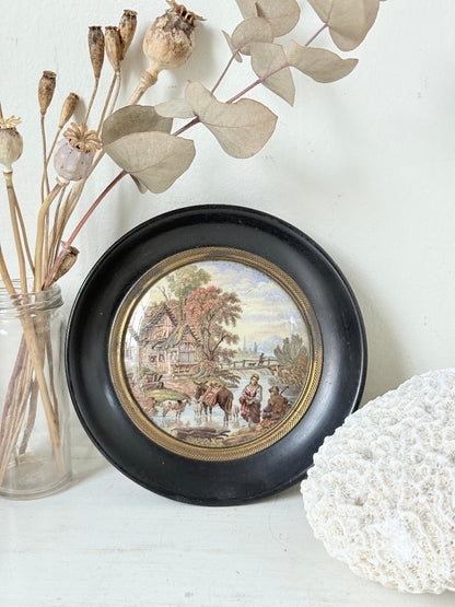 Antique Prattware framed pot lid with cottage scene photographed on a white surface.