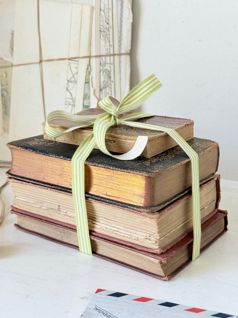 Vintage decorative book bundle with red burgundy cream and green hardback covers tied with green stripe ribbon for interior styling