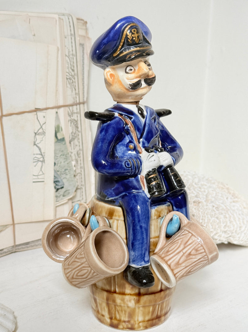 Vintage figural ceramic decanter set with captain, navy blue uniform, barrel base and 6 matching barrel shot cups