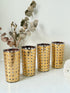 Set of 4 vintage gold rattan effect glasses with pierced lattice sleeves, photographed on a white surface
