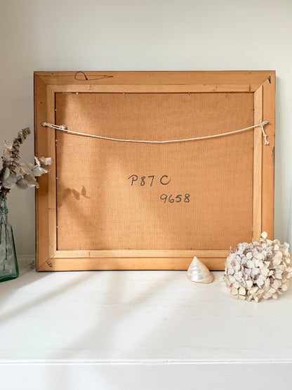 The back of a wooden picture frame leaning against a white wall on a white surface, with handwritten numbers &