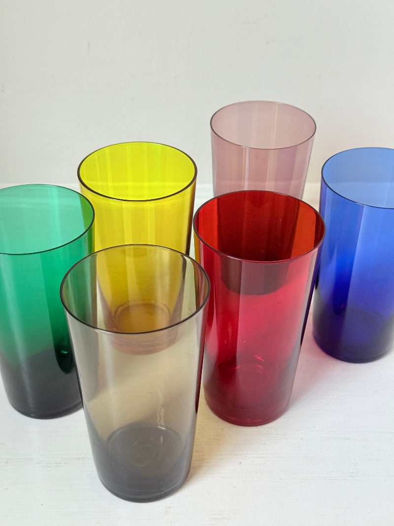 Set of six mid-20th century Boussu coloured glass tumblers in green, yellow, red, violet, blue and brown, photographed on white surface.