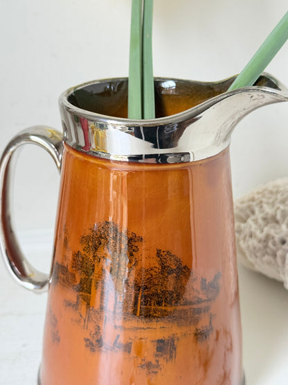 Antique Ridgways stoneware jug photographed on a white surface in amber treacle glaze with black Coaching Days and Coaching Ways scenes and silver lustre rim