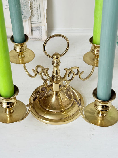 Brass five light candelabra with scrolled arms and a central ring handle on a domed base, photographed on a white surface