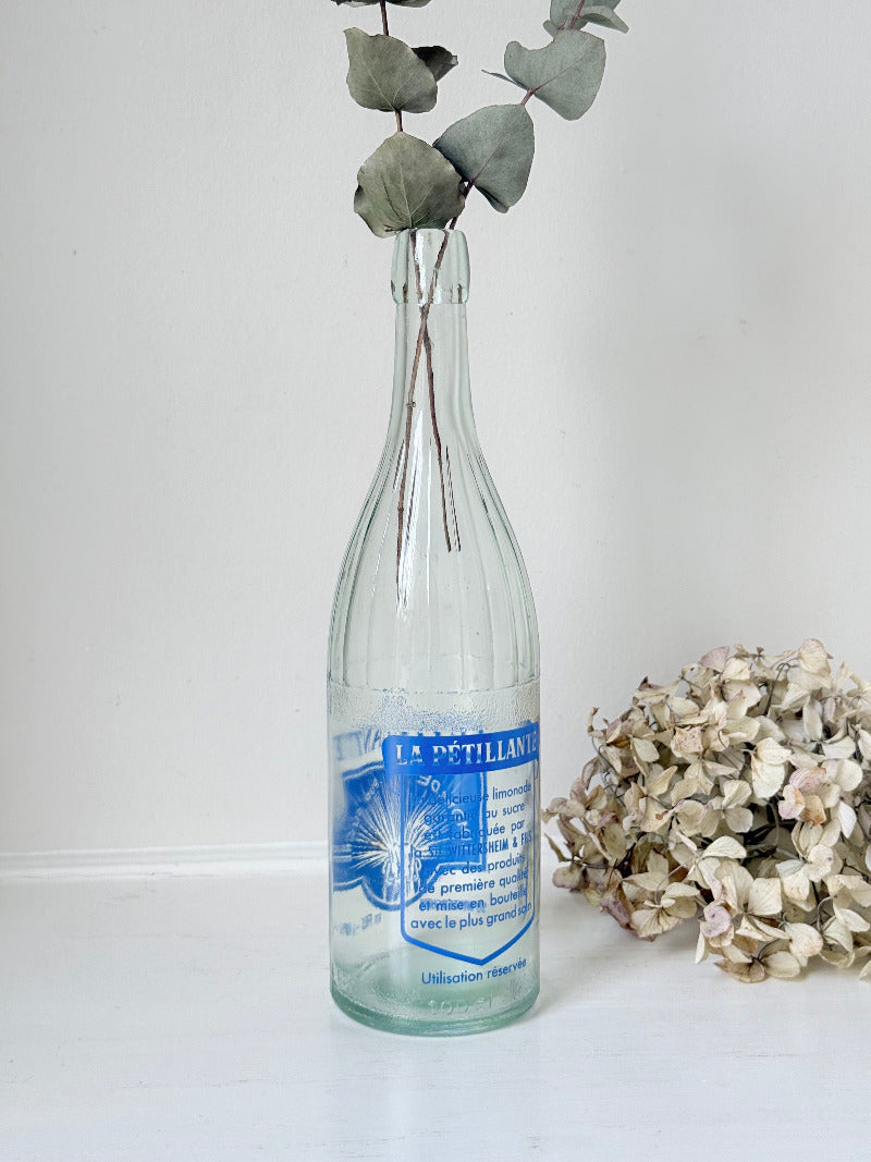 vintage french lemonade bottle la pétillante blue label on white surface with hydrangea flowers