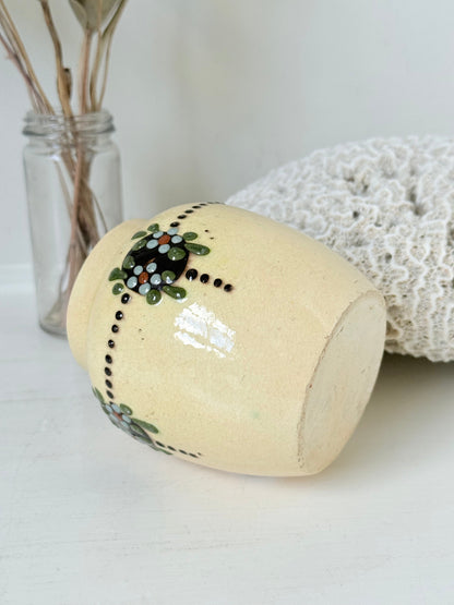 Cream studio pottery decorative pot with raised green floral motif, photographed on a white surface