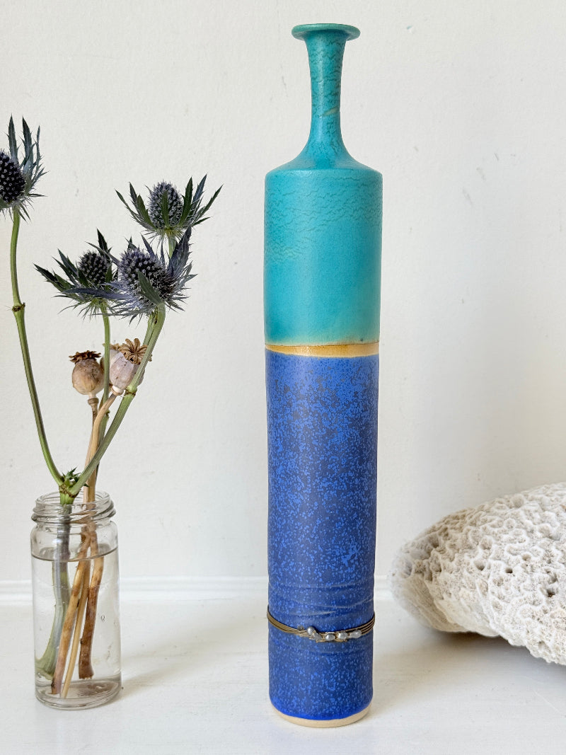 Tall vintage studio pottery bottle vase in turquoise and cobalt blue glaze, photographed on a white surface