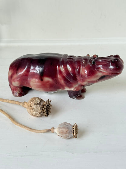 Red polished stone hippopotamus ornament displayed on a white background.