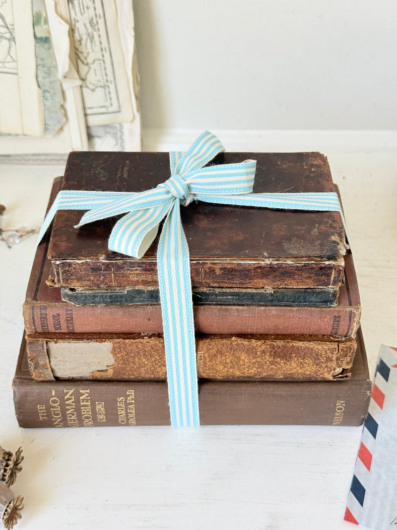 Vintage decorative brown book bundle with aged hardback covers tied with blue stripe ribbon for bookshelf and table styling