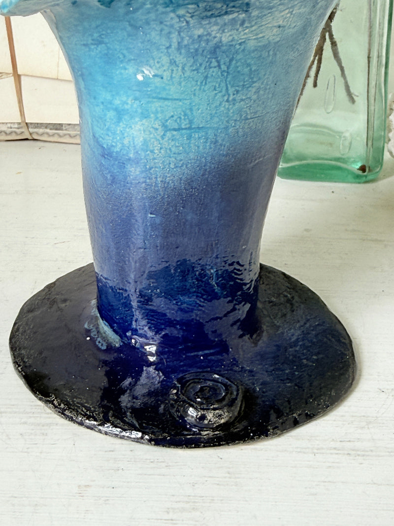Handmade studio pottery trumpet vase in ombre blue with a frilled rim, photographed on a white surface