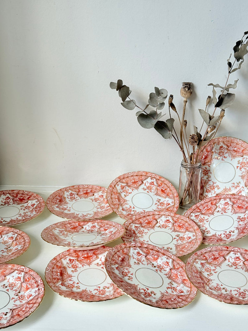 Set of 12 vintage coral transferware porcelain plates with scalloped edges and gold accents, 15 cm diameter, styled on a white surface.