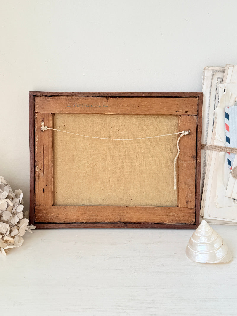 A rustic wooden picture frame with a natural jute canvas insert, shown from the back on a white surface with decorative seashells.