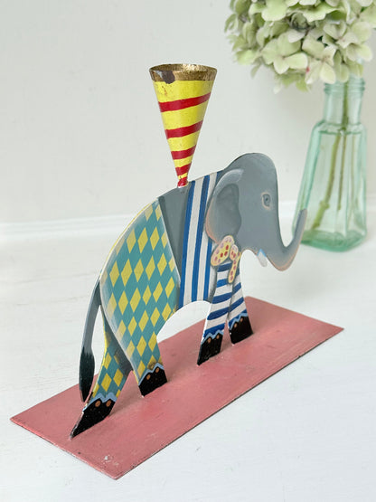 Hand painted metal elephant candlestick in circus-style decoration with colourful patterns, photographed on a white surface