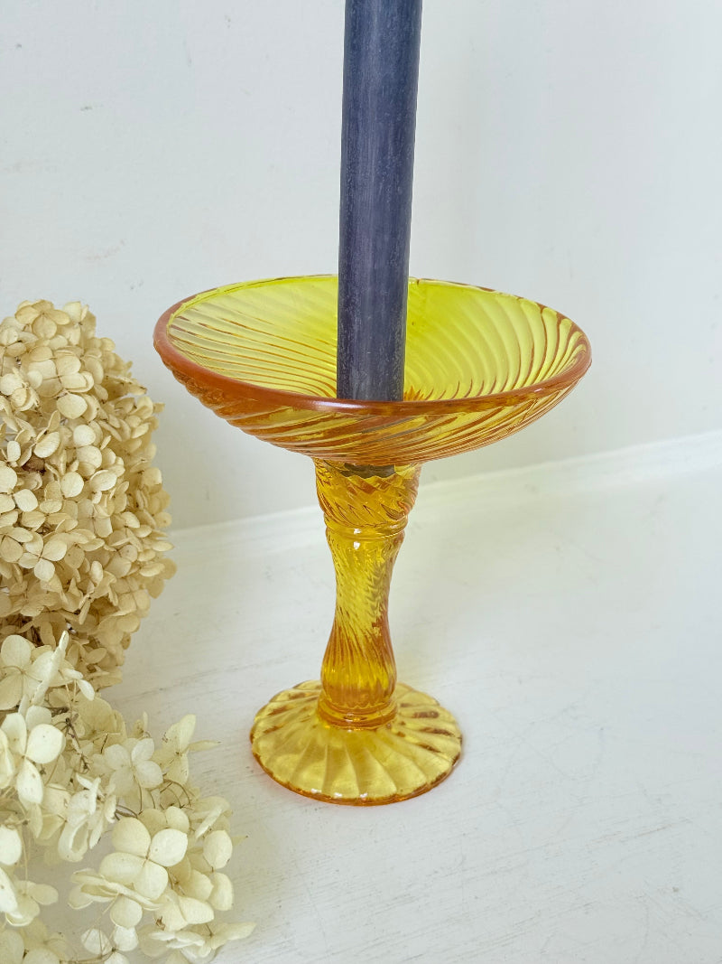 Amber pressed glass candle holder or compote with swirl design and pedestal base, photographed on a white background