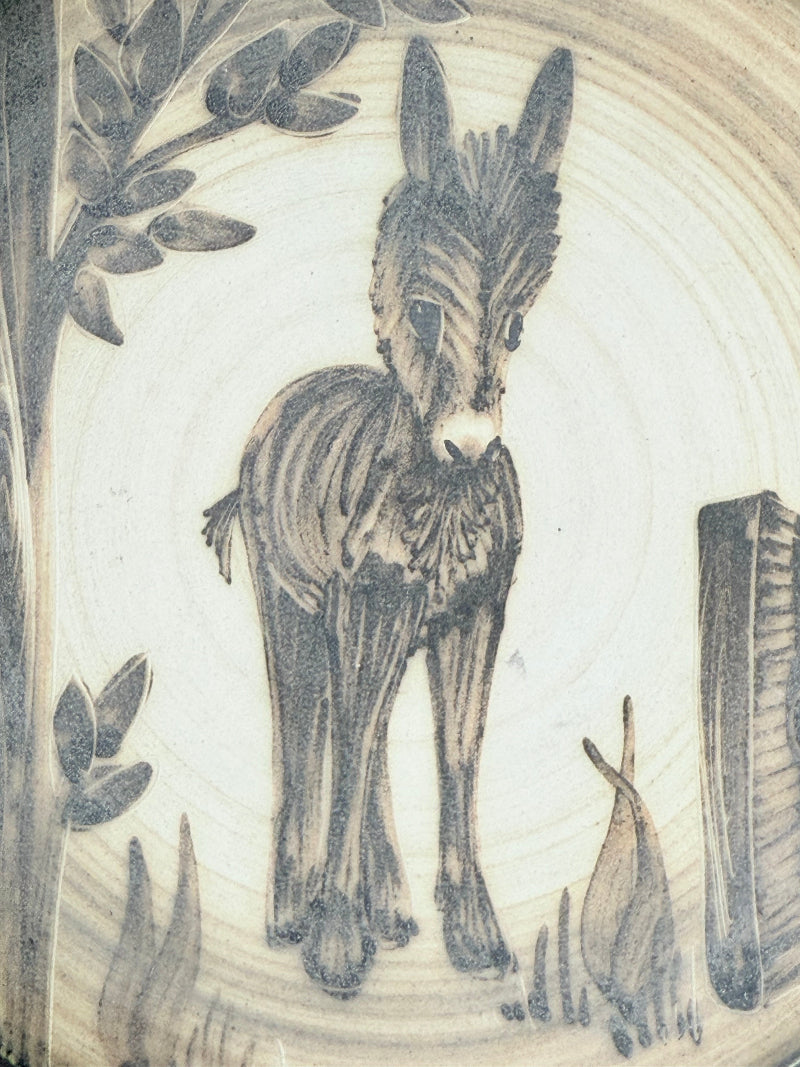 Vintage plate with hand painted brown donkey illustration and dark rim, photographed on a white surface