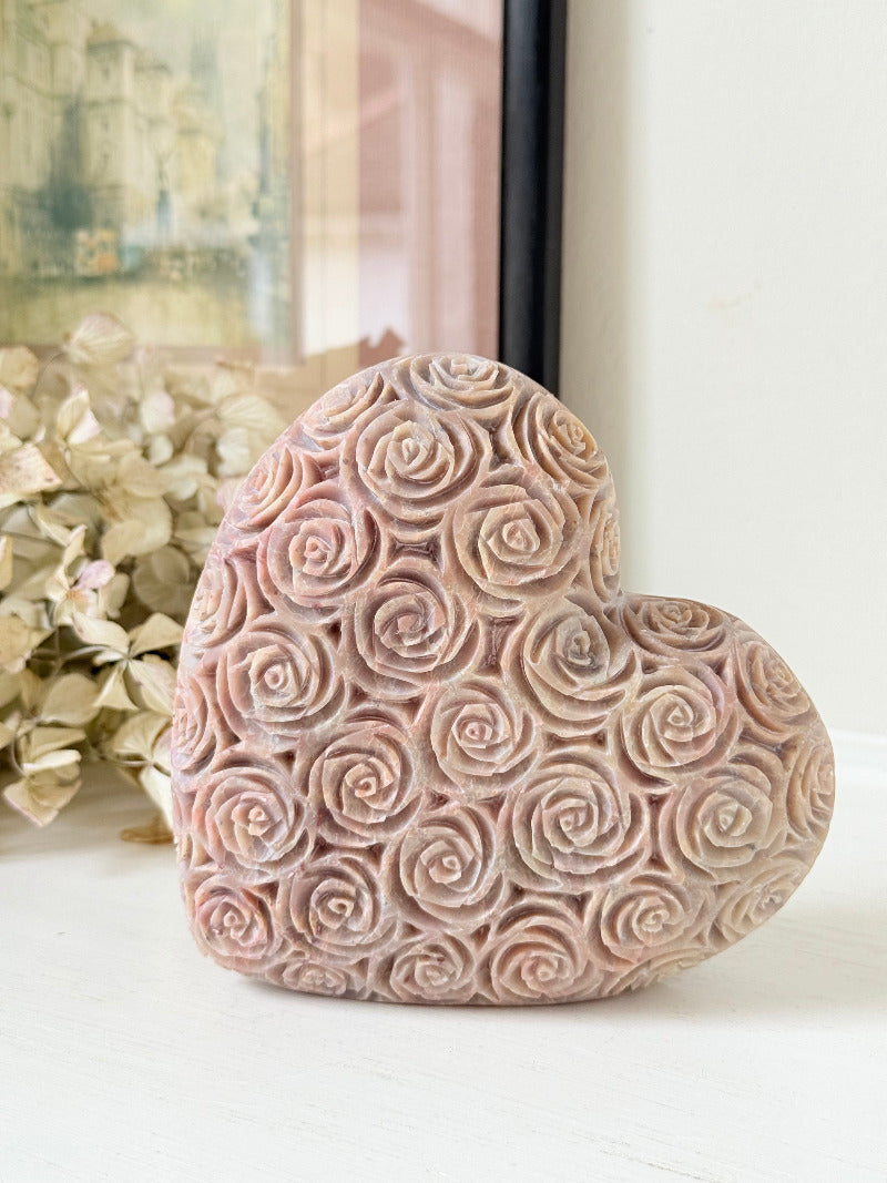 vintage pink stone heart with engraved roses and flat base on white surface